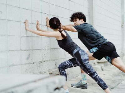 Man stretching his back against a wall
